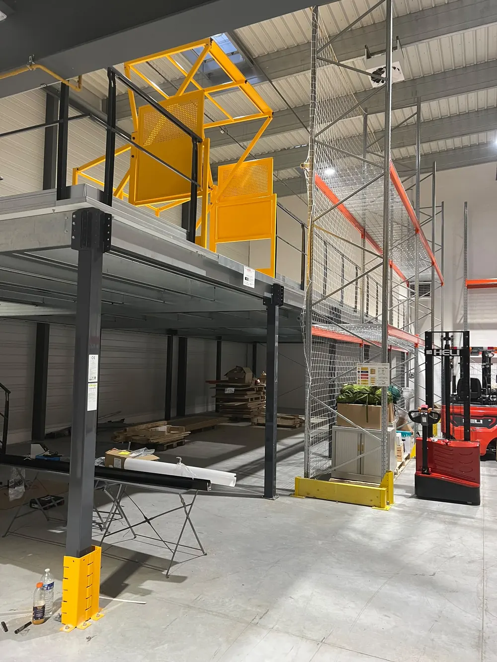 Mezzanine avec grillage de protection et zone de transfert par gerbeur