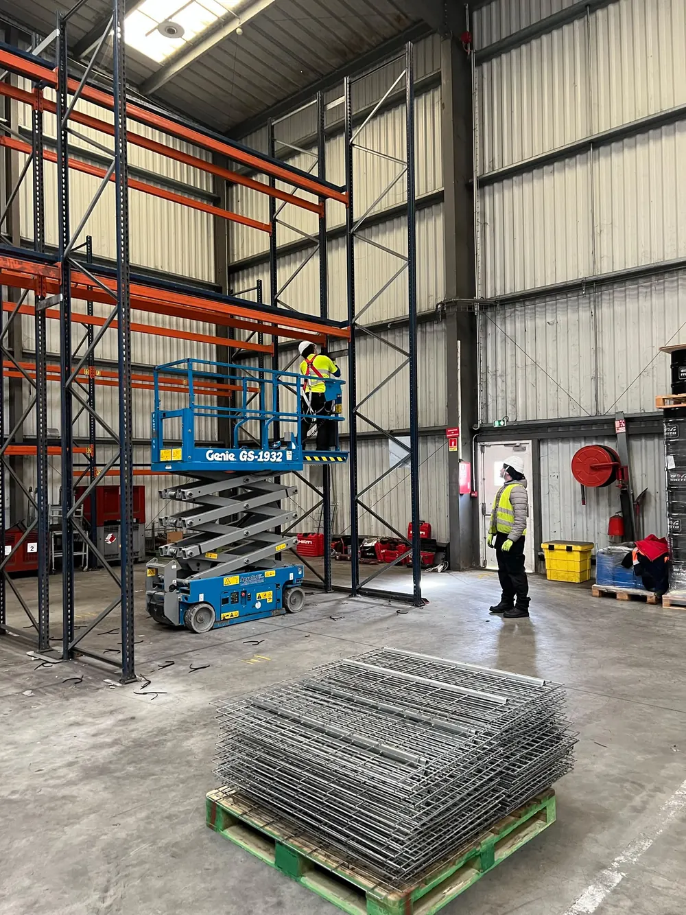 Montage de rack à palettes en nacelle ciseaux, zone balisée