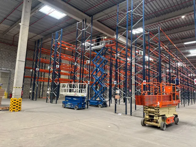 Trois nacelles en poste sur un chantier de rack à palettes